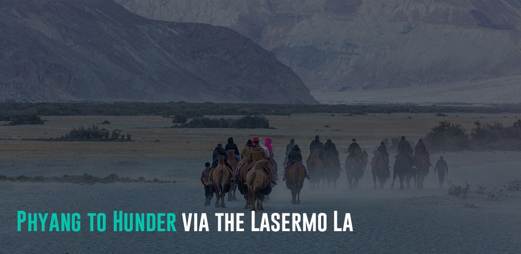 a group of people riding on camels toward the mountains