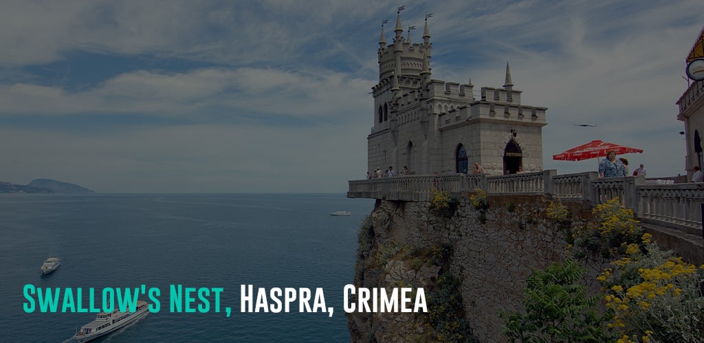 a castle on a cliff overviewing the ocean with boats