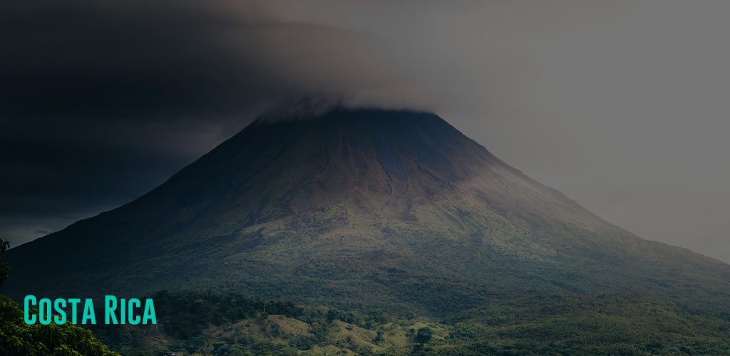 a very tall mountain/volcano with a very cloudy sky above it