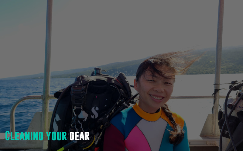 Woman being splashed from surf on a speed boat with scuba gear nearby.