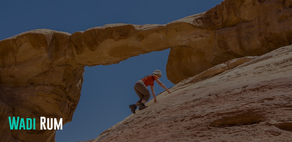 Woman climbing to the Burdah rock bridge in Wadi Rum desert, Jordan
