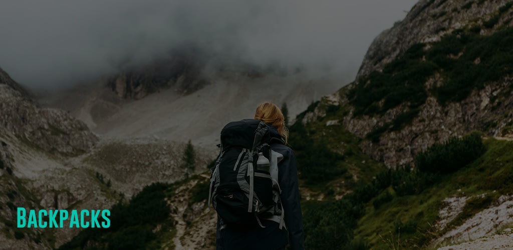 a woman with a backpack looking at the mountains as the clouds passes by